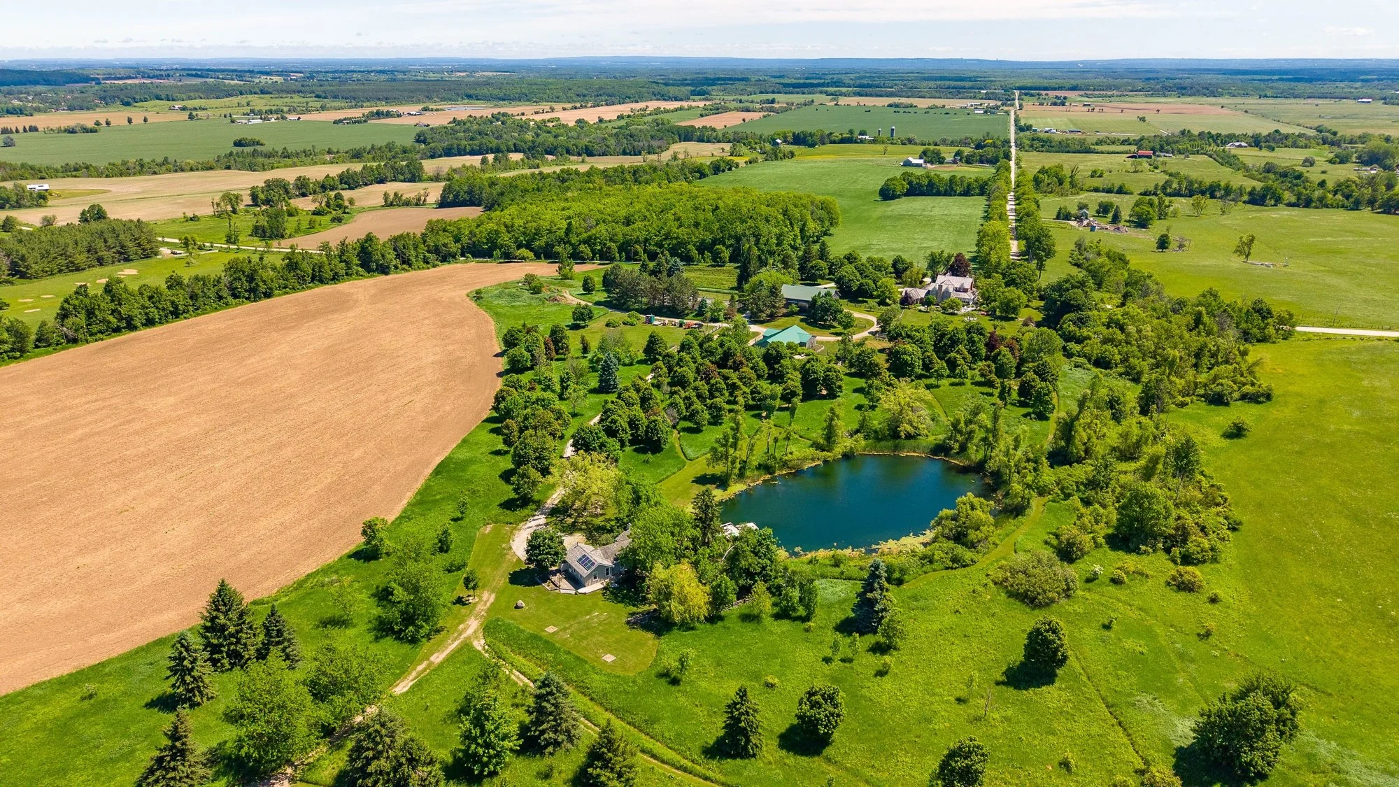 An aerial view of the farm's pond, green spaces and surrounding fields