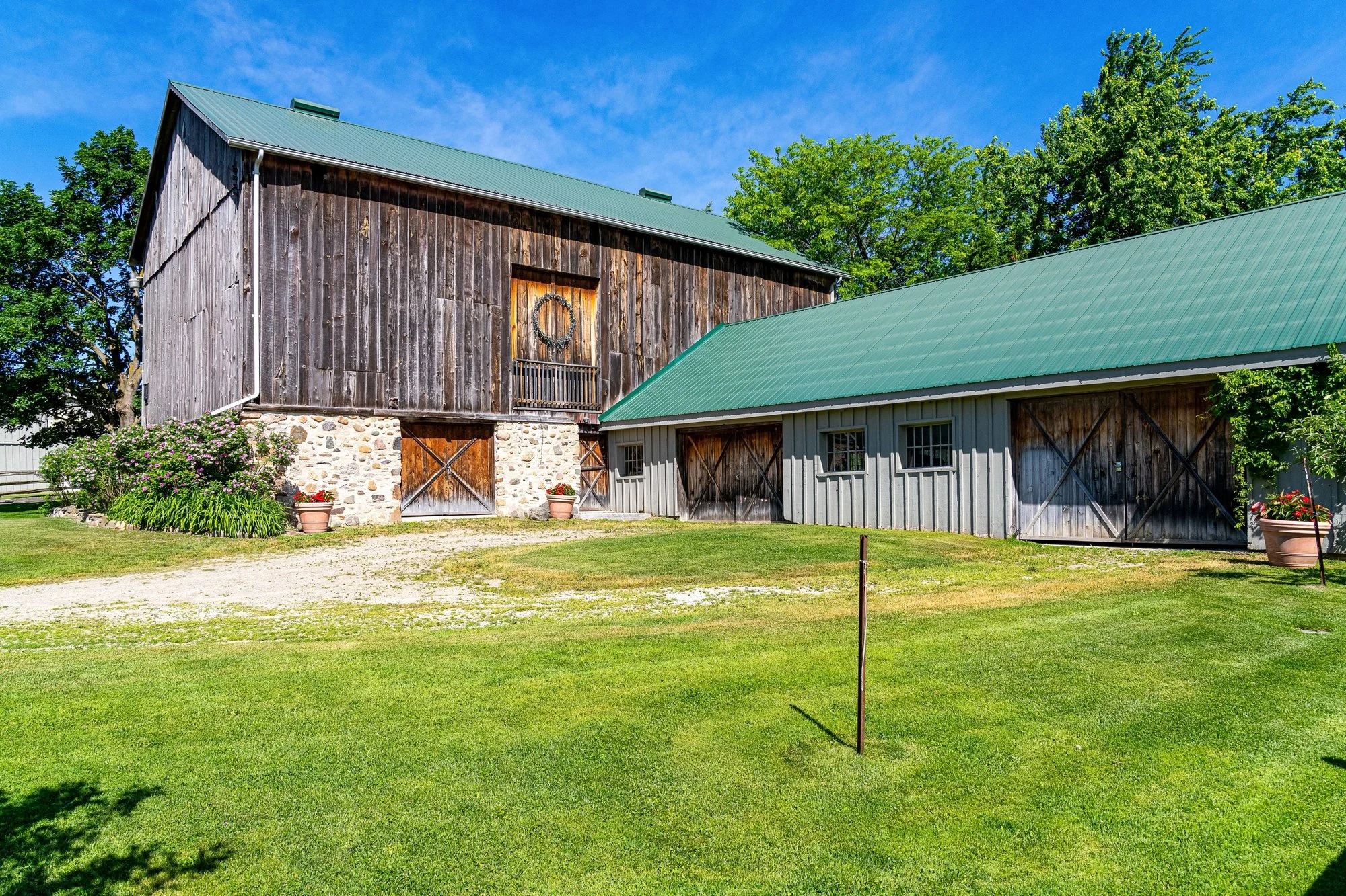 A timber barn with a green roof under blue summer skies
