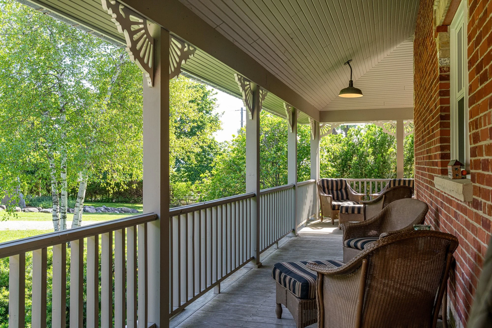 Chairs on the covered farmhouse porch looking out toward the gardens